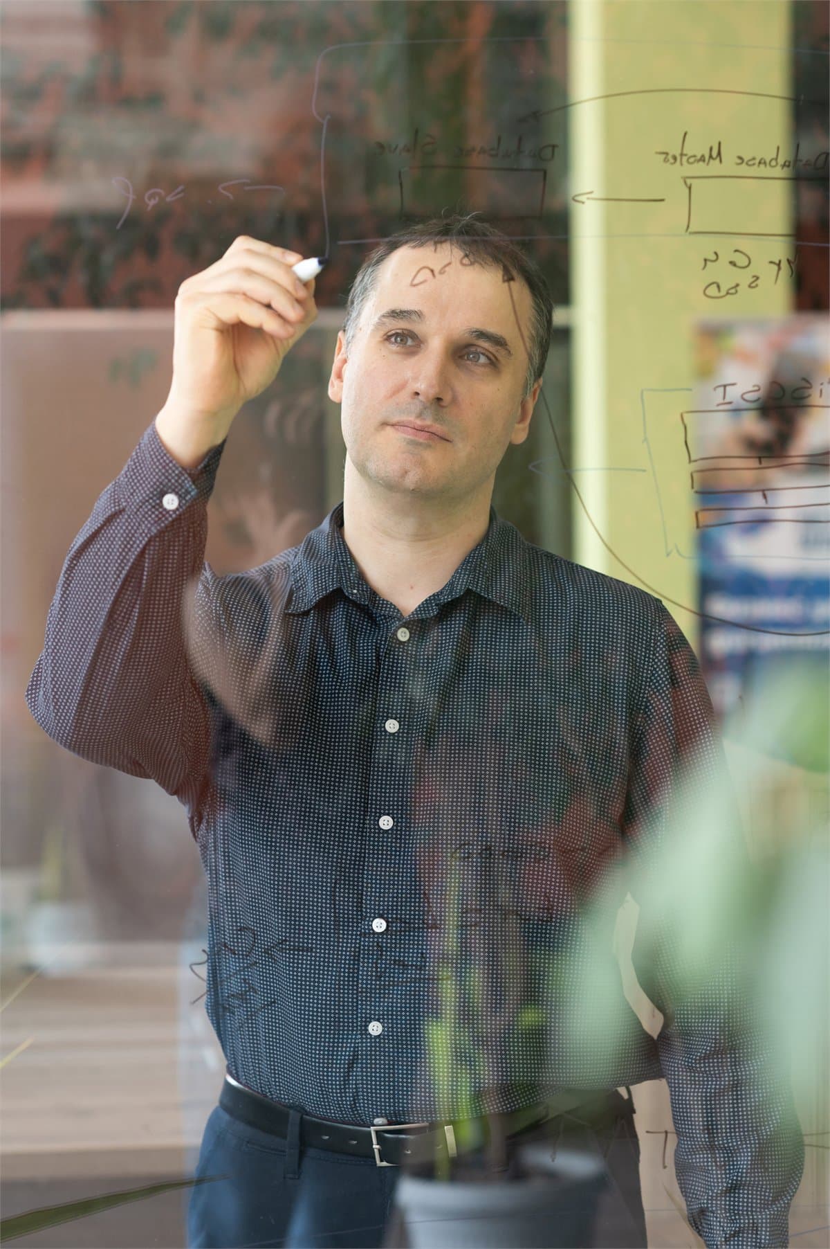 Ivan Yosifov writing and structuring a business system on a glass board.